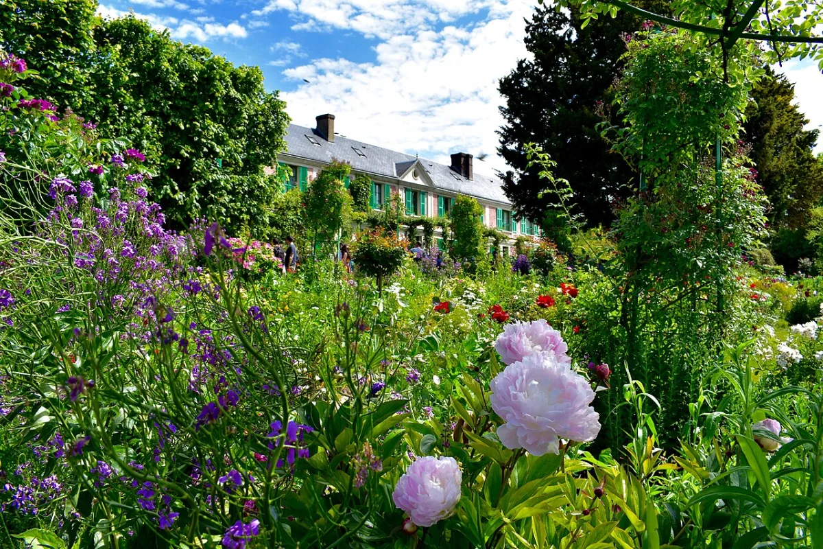 Het huis van Claude Monet gezien tussen bloeiende border in de tuinen van Giverny in het voorjaar